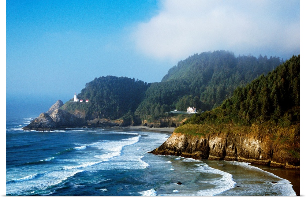 This landscape photograph shows waves striking against rocky sea cliffs covered with conifer trees on the Oregon coast.