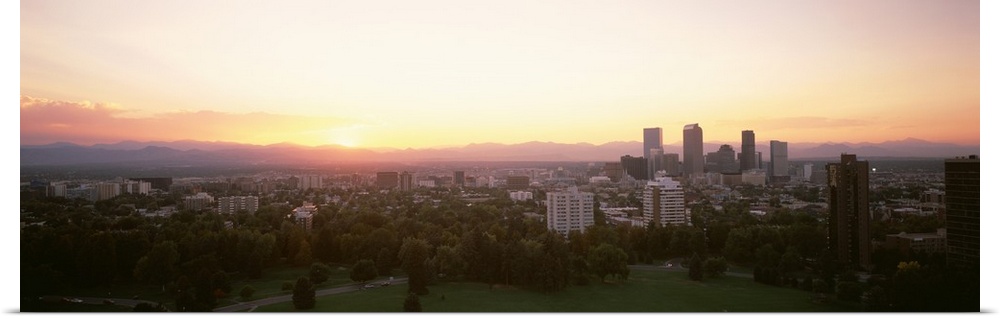 Panoramic photograph of the sunrise above the Denver, Colorado skyline and park.