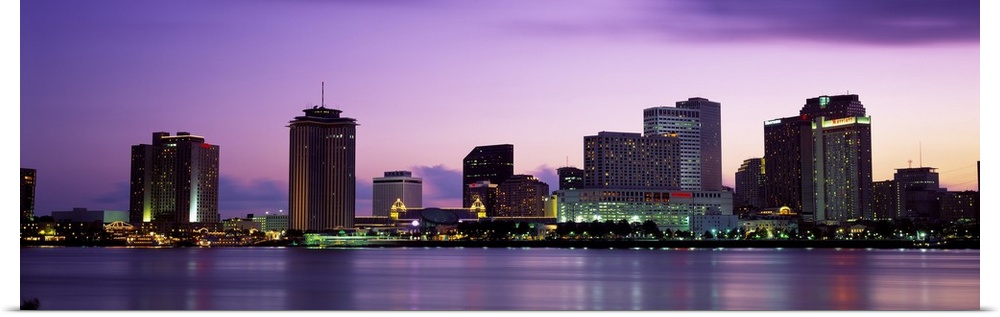 Sunset panorama of the Downtown New Orleans skyline with the Mississippi River in the foreground.
