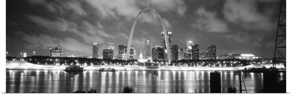A panoramic oversized canvas of the city skyline and Gateway Arch illuminated at night reflected in the Mississippi River.