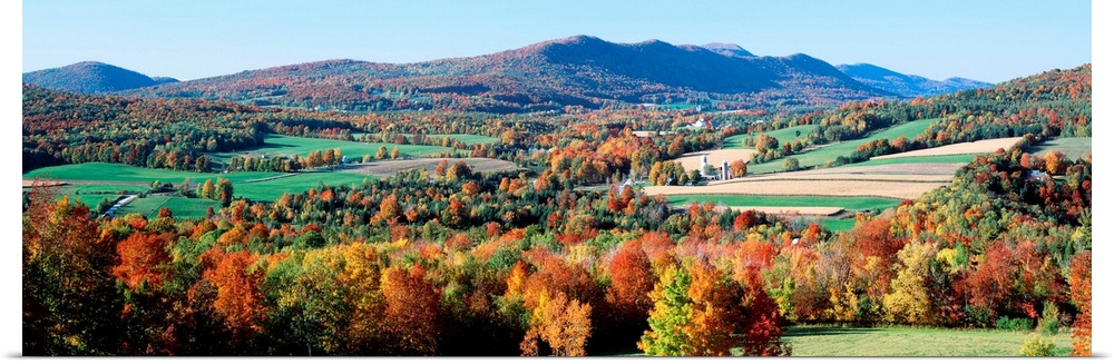 A valley in New England filled with open pastures and accented with trees covered with leaves turning in autumn.