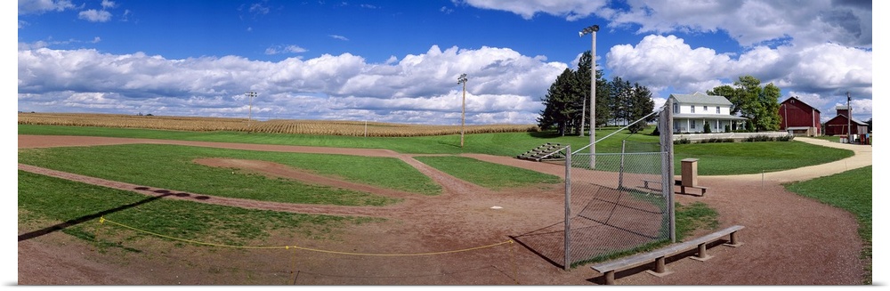 Landscape, large photograph of a baseball diamond on a farm, beneath a vast blue sky in Dyersville, Iowa.
