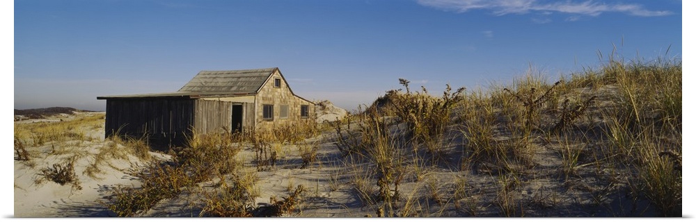 A shack sits on the beach just behind the dunes that are covered with grass.