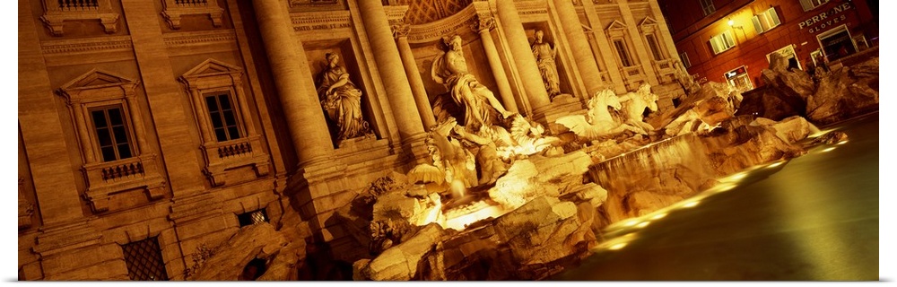 Panoramic canvas photo of Roman statues that are bathed in light at night.