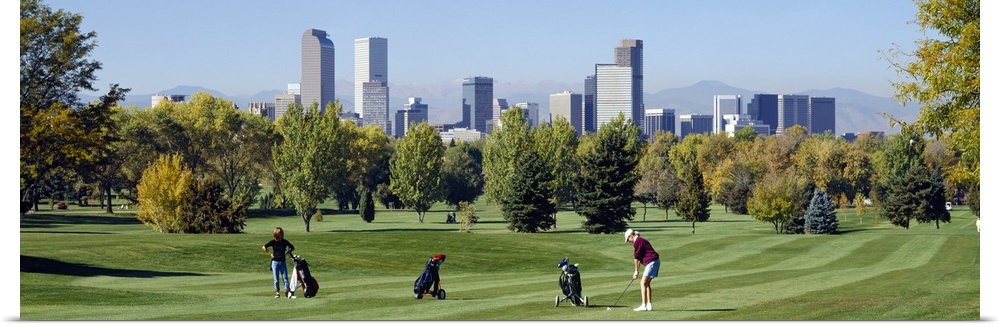 Four people playing golf with buildings in the background, Denver, Colorado
