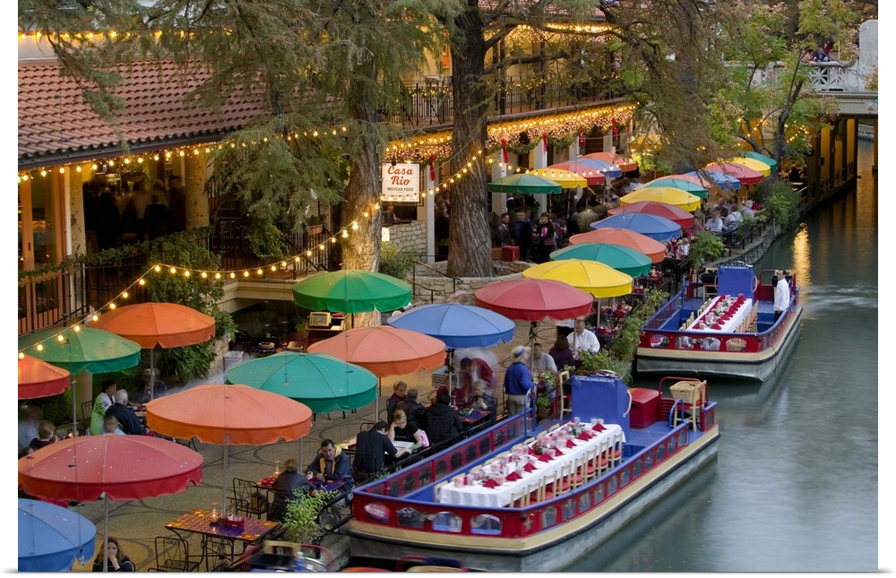 Large photo on canvas of colored umbrellas along a waterfront with boats with tables and chairs docked next to them.