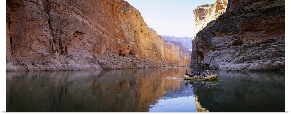 Large panoramic shot of an inflatable raft drifting down the tranquil Colorado River in the Grand Canyon.