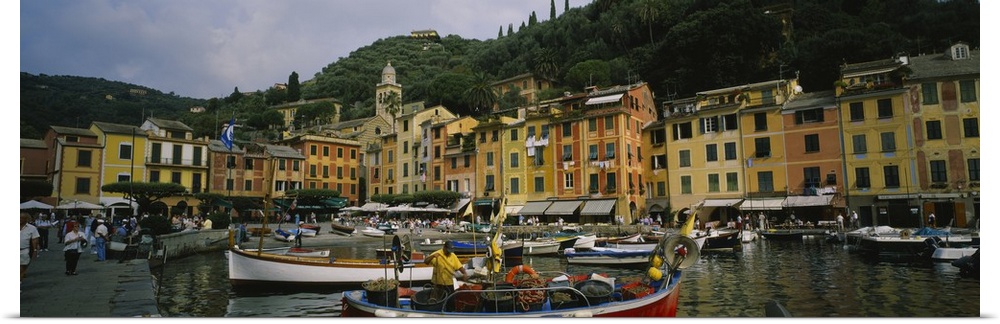 Panoramic canvas of an Italian boat harbor with a bunch of boats and buildings meeting the water in the background.