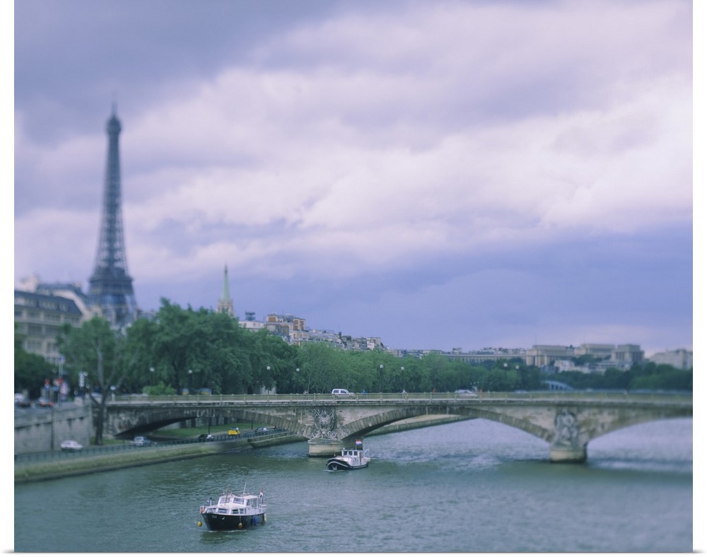 Horizontal photograph on a large canvas of  two small boats that have passed below a bridge on the Seine River, the Eiffel...