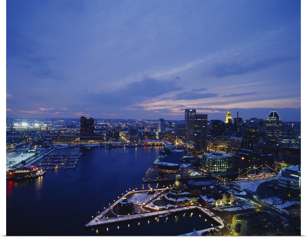 Large photograph taken from an aerial view over the calm waters of the Inner Harbor within a busy city in the Northeastern...
