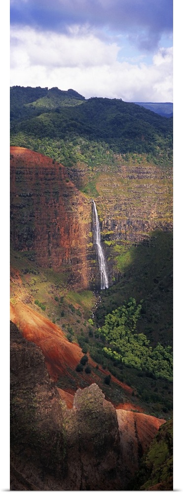 Tall photo on canvas of a waterfall flowing off of a giant cliff seen from a distance.