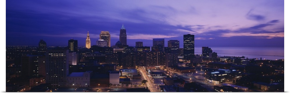 Panoramic, large photograph from a high angle of the Cleveland skyline, with lit buildings at night.