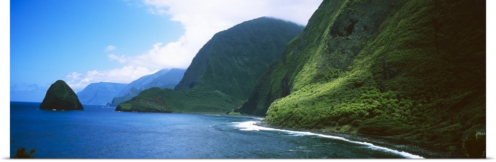 Panoramic photo of large tropical mountains meeting the ocean with a small mountain off shore.
