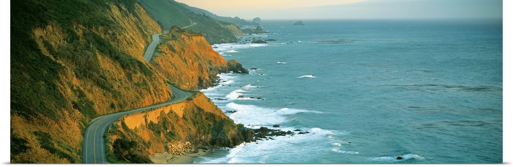 Giant, landscape, panoramic photograph of Highway 1 curving through a cliffside near the shoreline in Big Sur, California.