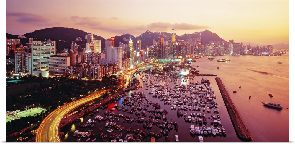 Large photograph of a harbor in Hong Kong at sunset. Hundreds of boats and many buildings can be seen.