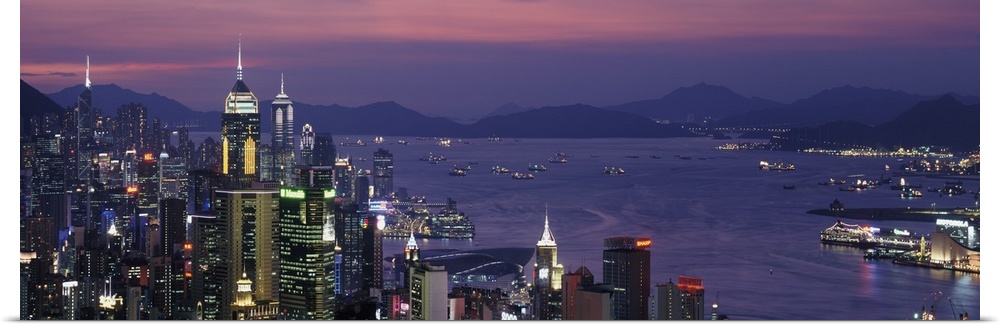 Panoramic image of twilight and the Hong Kong skyline and water by the city.