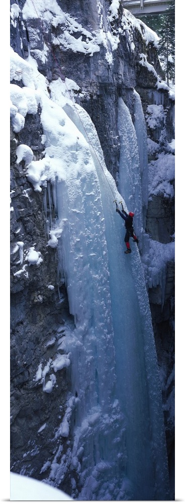 Vertical panoramic photograph of climber on ice covered rock.