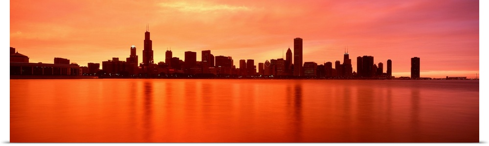 Panoramic photograph of skyline silhouette and waterfront at dusk.