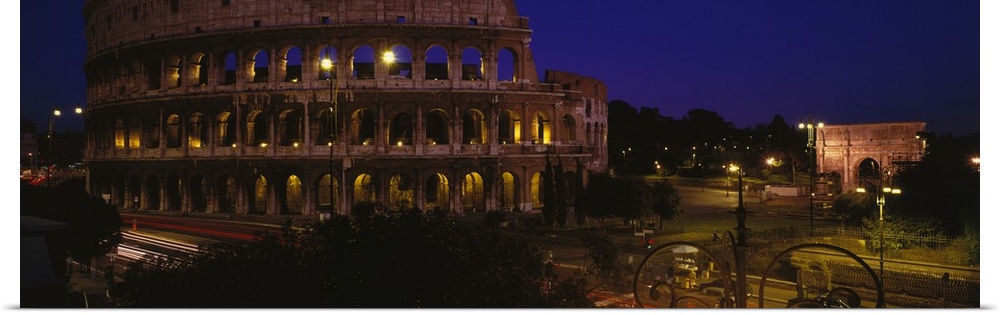Wide angle photograph of the Coliseum, lit up at night, in Rome, Italy.
