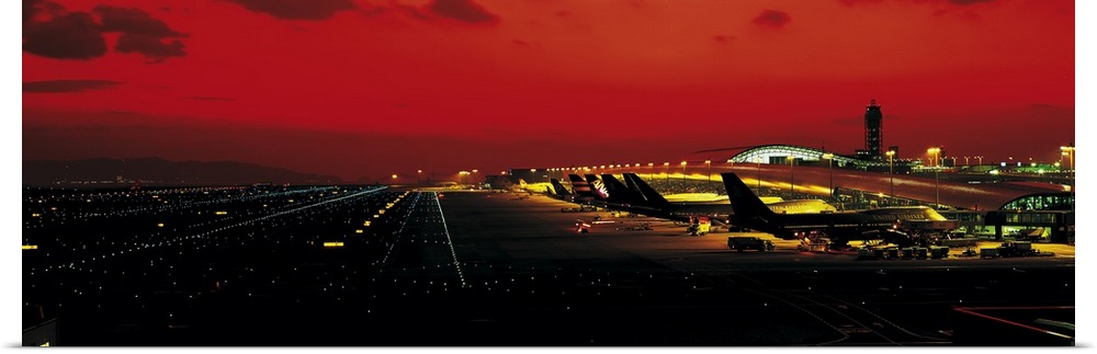 High angle photograph on a horizontal wall hanging of a line of aircraft surrounded by the lights and runway at Kansai Int...