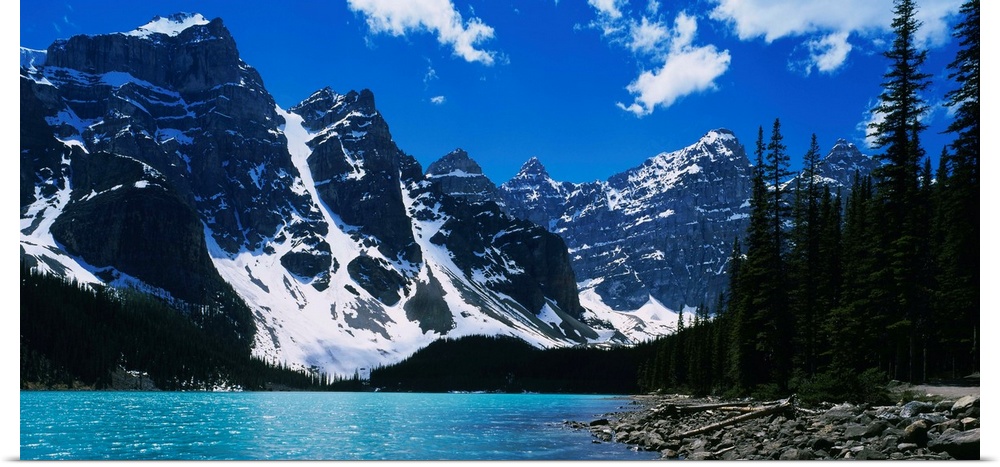 A landscape photograph of snow covered mountains surround a lake on this horizontal wall art.