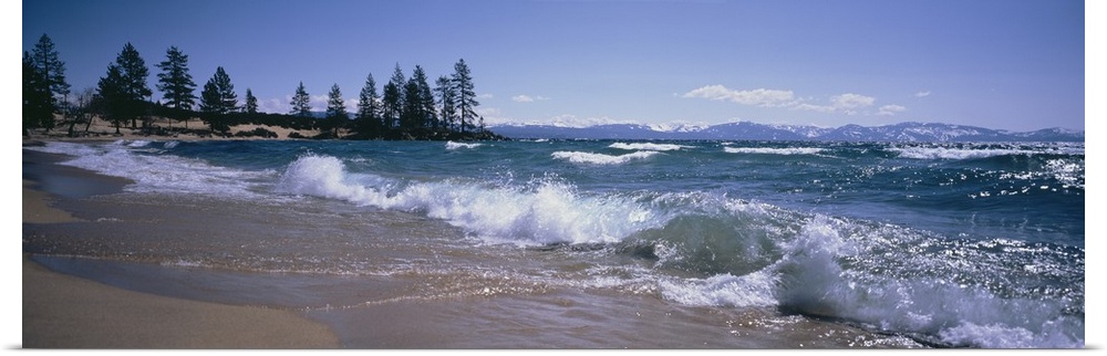 Panoramic photograph shows the waves of a large body of water in Nevada crashing against a sandy shoreline scattered with ...