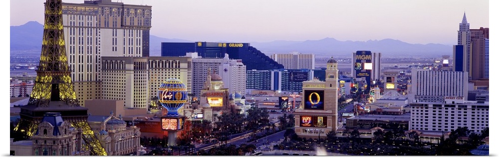 Panoramic photograph of ""Sin City"" skyline with mountains in the distance.  The buildings are lit up and the neon signs ...