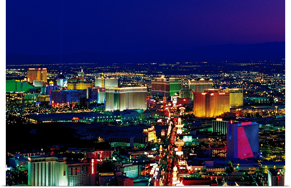 View from above of the Las Vegas strip its neon lights glowing in the night sky in a horizontal photograph.