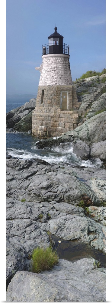 This is a vertical photograph of light house on a rocky coast.