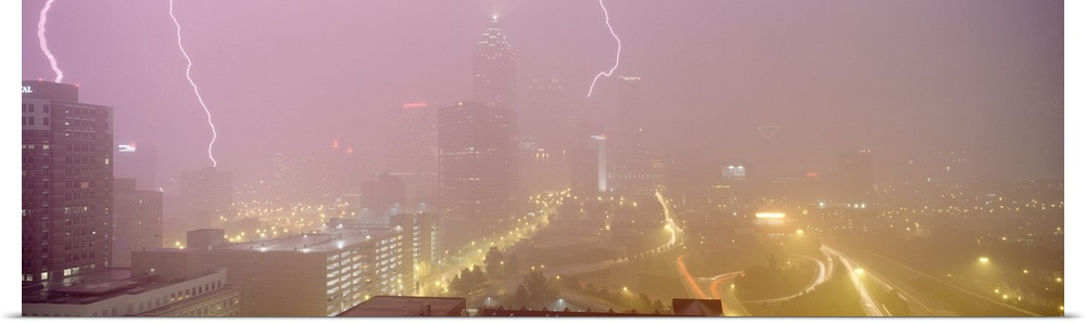 Panoramic photograph of skyline with storm clouds and lightning bolts overhead.