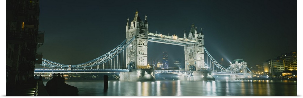 Panoramic photograph taken of the London tower bridge illuminated under a dark night sky.