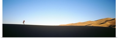 Low angle view of a woman running in the desert, Great Sand Dunes National Monument, Colorado