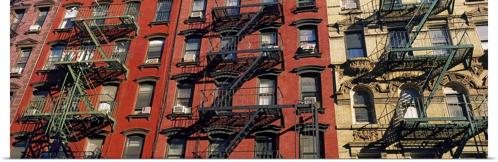 Panoramic image of iron fire ladders on the sides of apartment buildings in an urban city, creating industrial patterns.