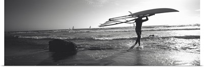 Man carrying a surfboard over his head on the beach, Santa Cruz, California