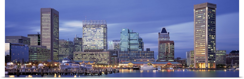 This large panoramic photograph is of the Baltimore skyline at dusk with cool colors and the bulidings lit up.