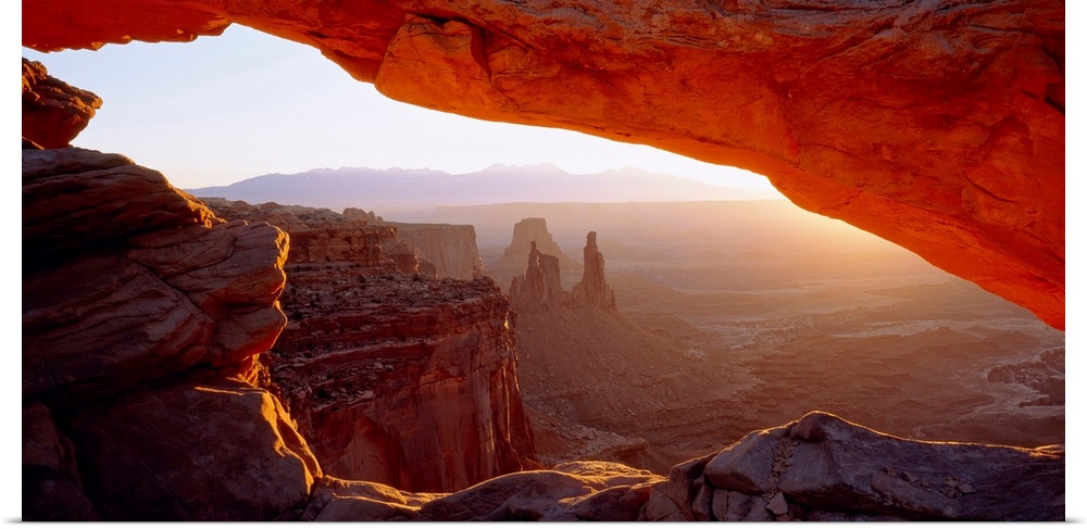 Wall art for the home or office this big picture shows a view of the desert at sunrise through a rocky arch.