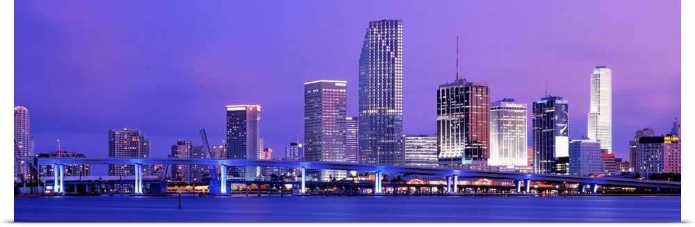 Wide angle photograph of brightly lit bridge and  skyscrapers of the Miami skyline at sunset.
