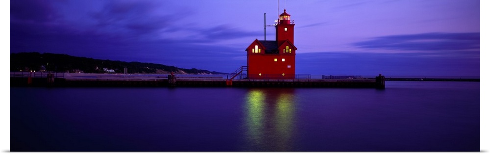 A brightly colored lighthouse reflecting light onto the water at night in Holland, Michigan.
