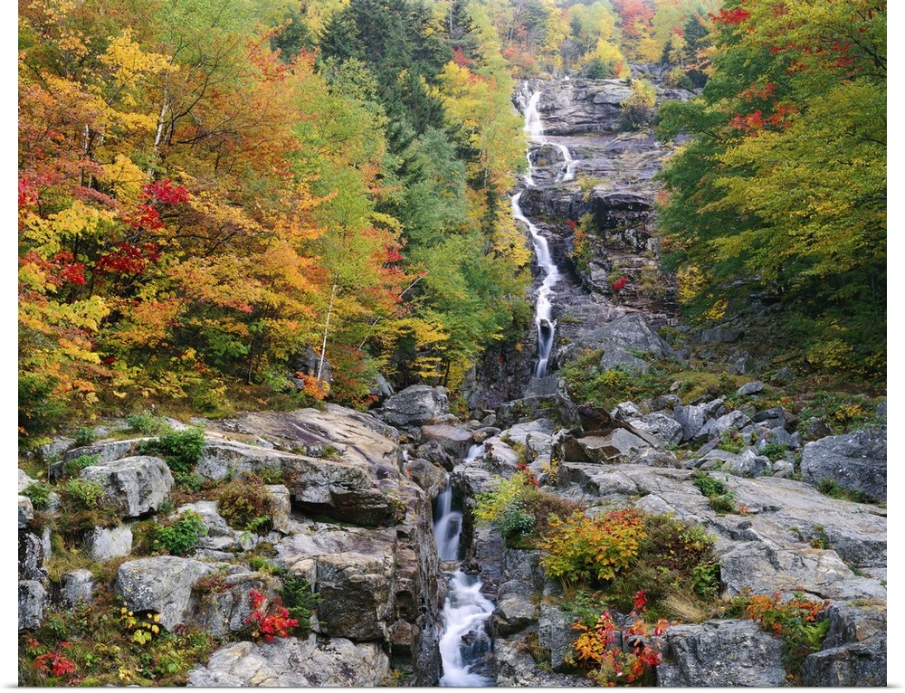 Photograph of waterfall surrounded by rocky terrain and a fall forest.