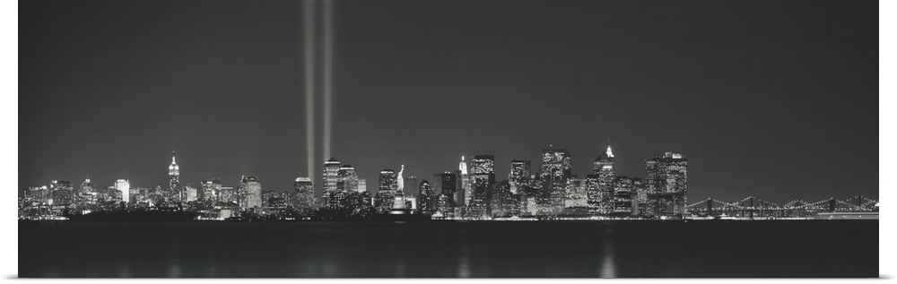 Panoramic vista of the New York City skyline in the evening, with beams of light from the World Trade Center tribute shini...