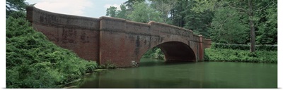 North Carolina, Asheville, View of a red brick arched bridge over river