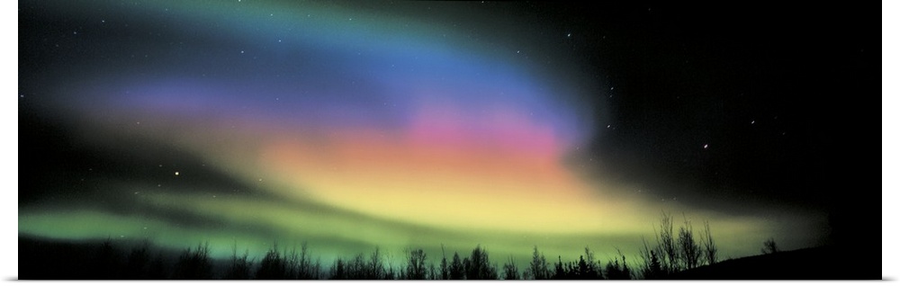Panoramic photograph taken of the northern lights. Swirls of color brighten the dark night sky.