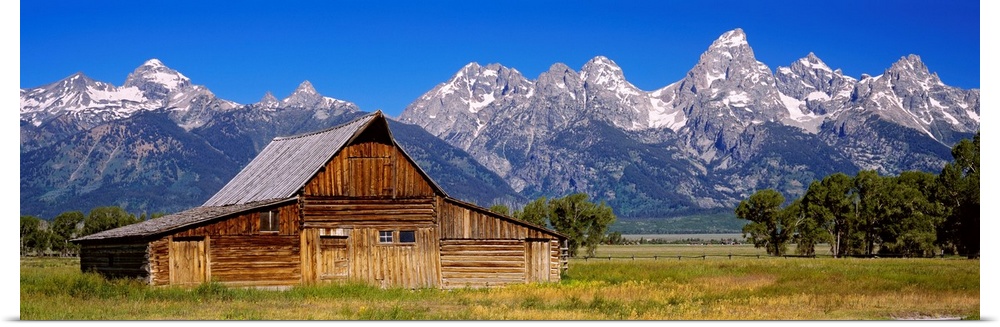A panoramic landscape photograph of farmland, the T.A. Moulton barn, and the massive mountain peaks in the background.