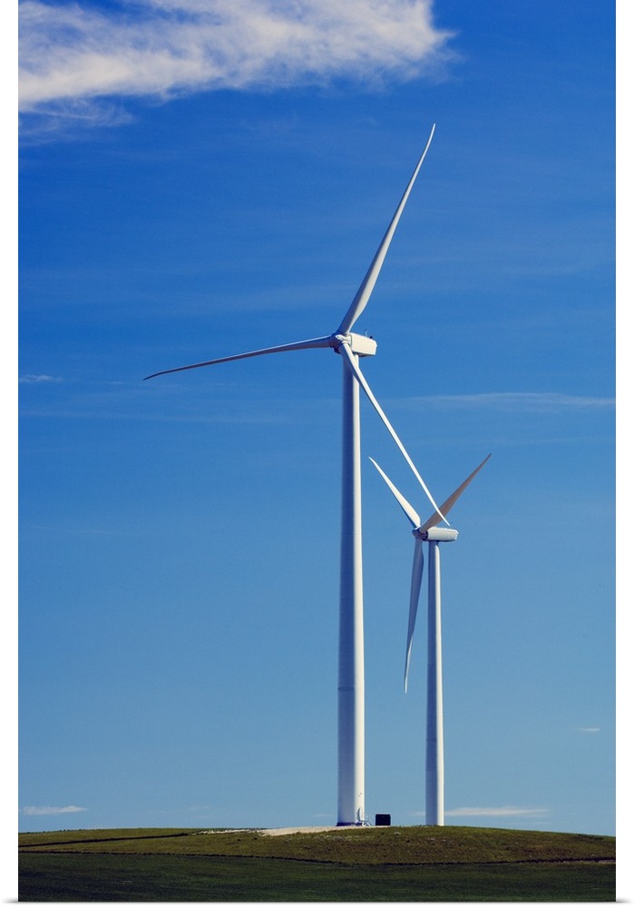 Pair of wind farm turbines in green grass, blue sky, Montana