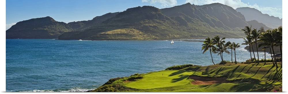 Panoramic photograph taken from a golf course of a large mountain across a lagoon in Hawaii.