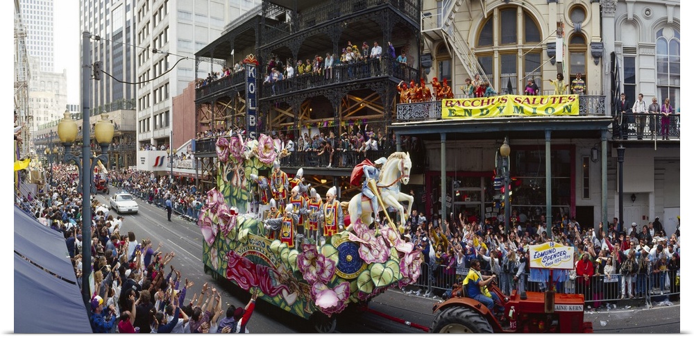 Large horizontal photograph of a tractor pulling a float through the crowded city streets of New Orleans, during the Mardi...