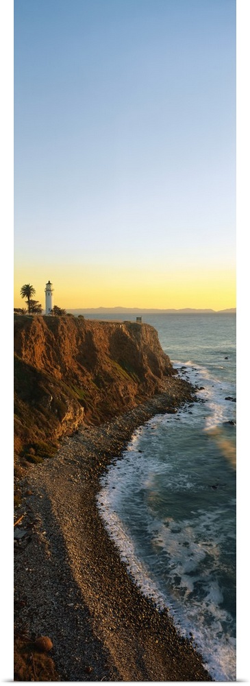 Vertical panoramic canvas of a lighthouse sitting on a cliff near the ocean at sunset.
