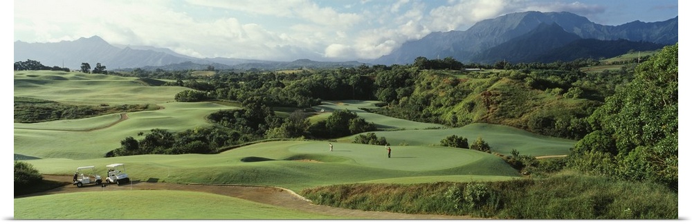 Panoramic picture of rolling hills of a golf course nestled in the Hawaiian mountains.