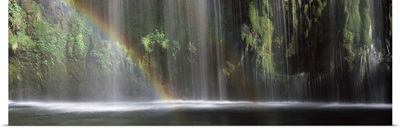 Rainbow formed in front of waterfall in a forest, California,