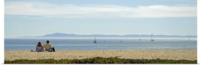 Rear view of a couple sitting on the beach, Channel Islands, Santa Barbara, California
